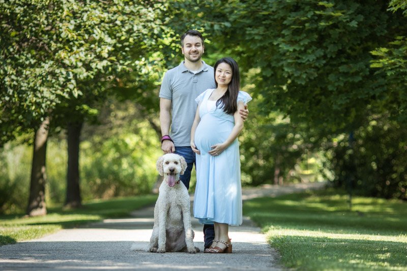 Maternity Mothers Day portrait. A pregnant girl and her husband, as well as their do, pose in a park setting