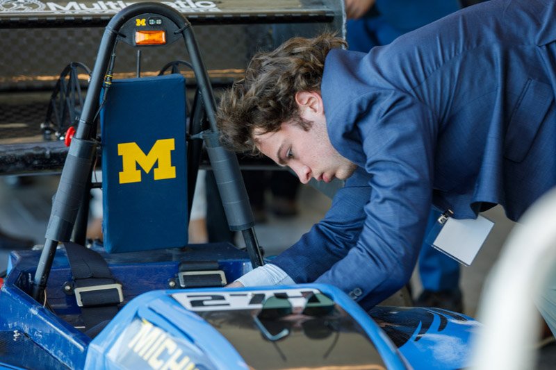 Guest inspecting University of Michigan race car at M1 Concourse event