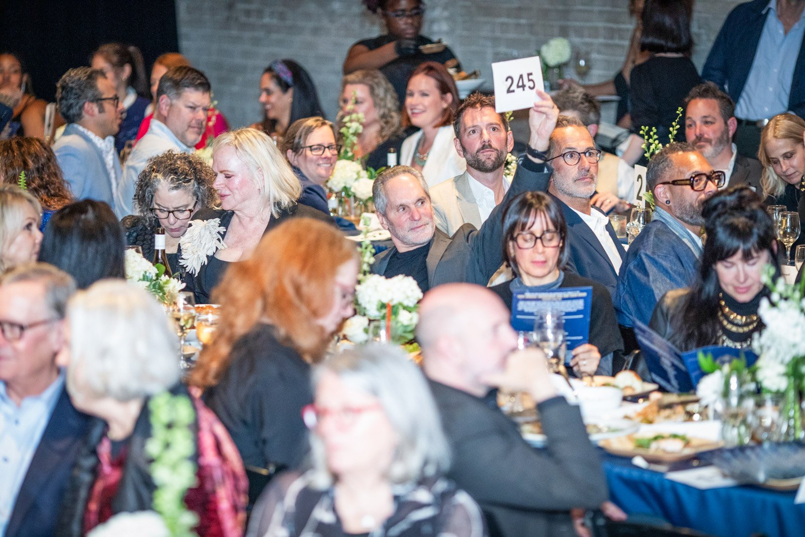 Nonprofit fundraising event in Detroit with guests participating in a live auction during a gala