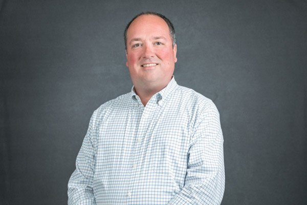 Professional conference headshot with studio lighting and gray background.