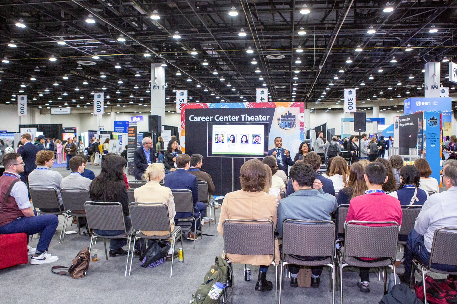 Conference attendees watching an educational presentation on the expo floor at Huntington Place in Detroit.