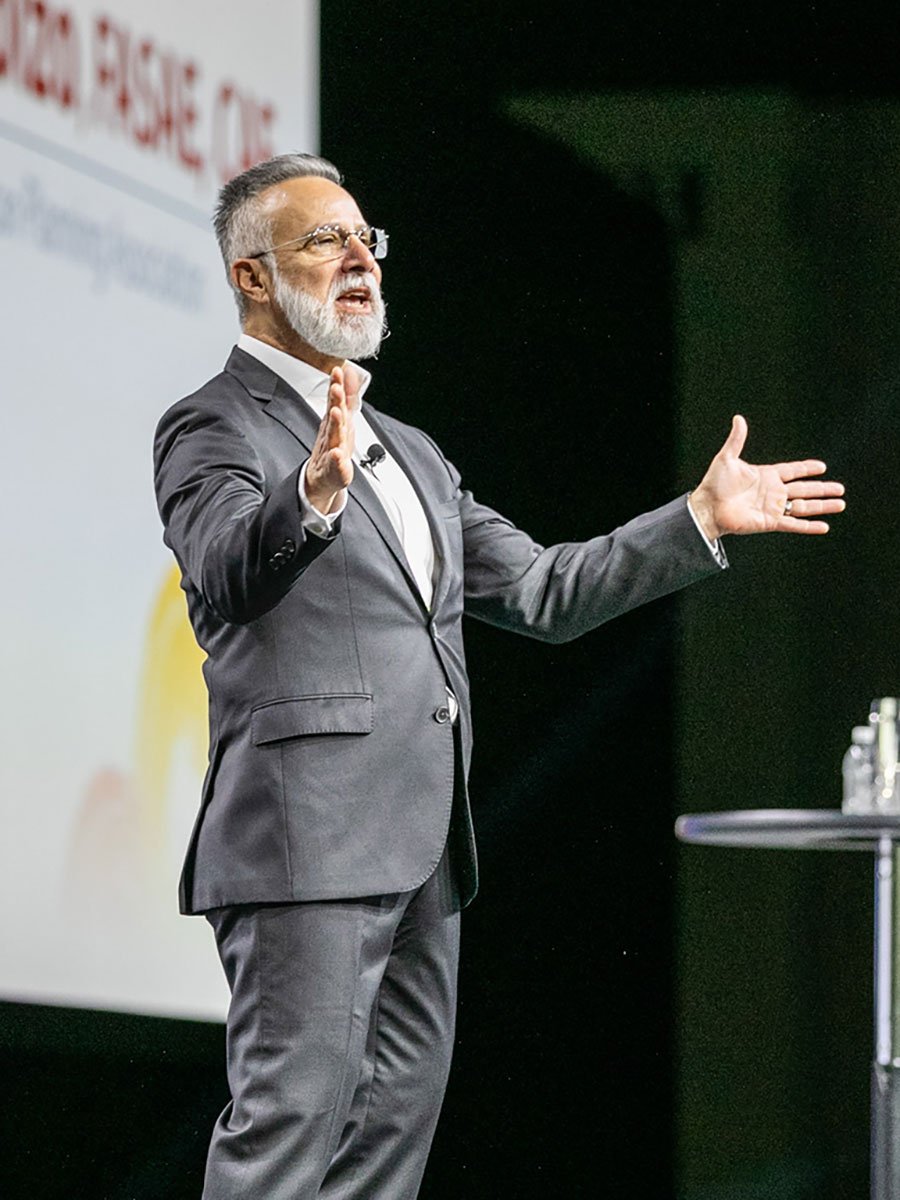 Keynote speaker presenting on stage during a corporate conference at Huntington Place in Detroit, Michigan.