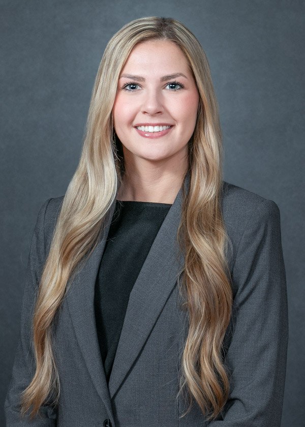 Professional ERAS headshot of a female medical residency applicant in a gray blazer with a neutral gray background.