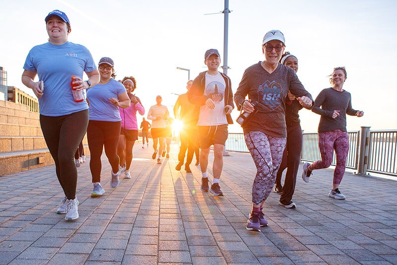 Conference attendees participating in a sunrise 5K run along the Detroit Riverwalk during a multi-day conference in Detroit.