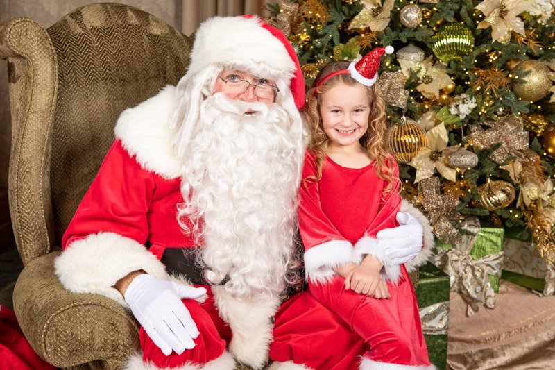Child photographed with Santa during the MNP Corporation holiday celebration at San Marino Club