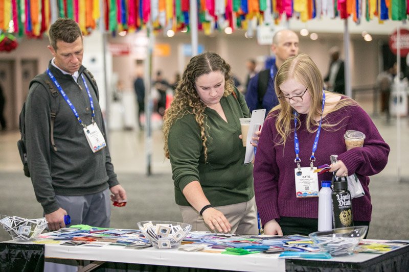 Trade show attendees talking with an exhibitor and viewing materials at a booth