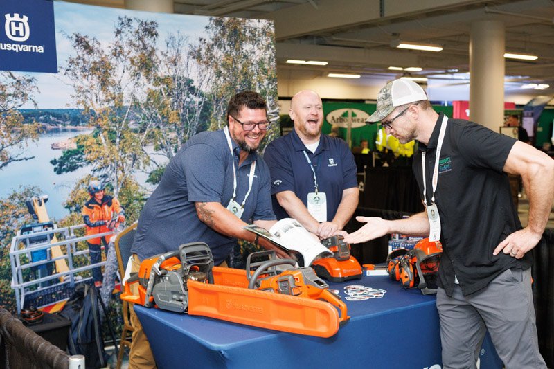 Husqvarna representative demonstrating equipment to an attendee at a trade show