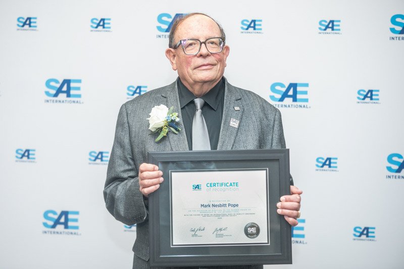 SAE award recipient photographed in front of a branded step and repeat backdrop, Detroit