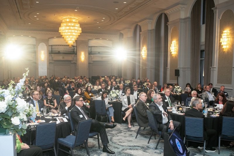 Guests seated at banquet tables during a formal corporate awards ceremony in an elegant ballroom.