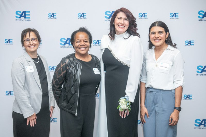 Four attendees pose together in front of an SAE International backdrop at a corporate awards event.